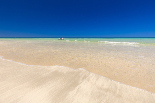 Feiner weißer Sandstrand, türkisblaues Meer, das nach hinten in ein tiefes Balu übergeht