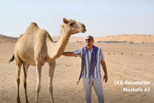 Mann steht neben Kamel, Reiseleiter f&uuml;r SKR